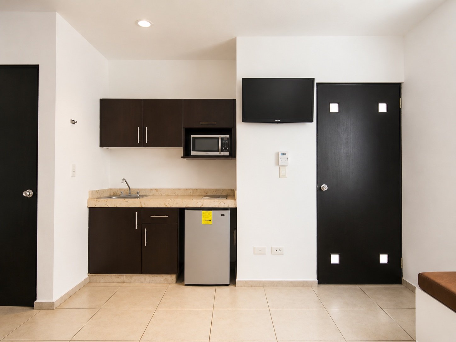 Cocineta equipada con microondas, refrigerador y televisión.